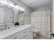 Bright bathroom with double vanity, framed mirrors, updated lighting and decorative shower curtain at 243 Wedmore Ct, Suwanee, GA 30024