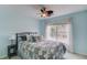 Cozy bedroom with blue walls, ceiling fan, large window and colorful quilt on an iron bed frame at 243 Wedmore Ct, Suwanee, GA 30024