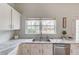 Elegant kitchen counter with tile backsplash and stainless steel dishwasher under a window at 243 Wedmore Ct, Suwanee, GA 30024