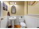 Charming half bathroom featuring wainscoting, a pedestal sink, decorative mirror, and a woven hanging decor item at 1677 Angelica Ct, Lawrenceville, GA 30043