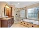 Elegant bathroom with a soaking tub, tiled shower, vanity, and decorative window at 1355 Zephyr Ct, Cumming, GA 30041