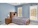 A charming bedroom with light blue walls, a cozy bed, and a delightful view from two bright windows at 1355 Zephyr Ct, Cumming, GA 30041