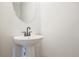 Half bath with white pedestal sink and round mirror at 409 Carrera Ln, Acworth, GA 30102