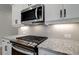 Close up of the kitchen features stainless steel appliances and granite countertops with modern backsplash at 409 Carrera Ln, Acworth, GA 30102