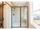 Modern walk-in shower with glass enclosure and black trim, complemented by tiled walls, a built-in bench, and a window at 409 Carrera Ln, Acworth, GA 30102