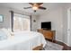 Comfortable bedroom featuring a ceiling fan, dresser with television, and large windows with a wooded view at 6435 Ivey Creek Cir, Cumming, GA 30040