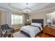 This bedroom offers a tray ceiling with chandelier, a large window and hardwood floors at 950 Brook Knoll Ln, Cumming, GA 30041