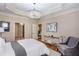 A bedroom featuring a tray ceiling, recessed lighting, and an adjacent sitting area at 950 Brook Knoll Ln, Cumming, GA 30041