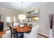 Chic dining area featuring a round wooden table, modern lighting, and a clear view into the well-appointed kitchen at 950 Brook Knoll Ln, Cumming, GA 30041
