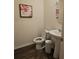 Cozy powder room featuring a pedestal sink, wood floors, floral art and a round mirror at 623 Wayland Ct, Fairburn, GA 30213