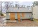 Back exterior of home with boarded-up doors, a gray roof, and a muddy yard at 2370 Wingfoot Pl, Decatur, GA 30035