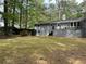 Spacious backyard with a grey brick house, deck, and lush greenery, surrounded by mature trees at 2899 Tejas Sw Trl, Atlanta, GA 30331