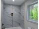 Luxurious bathroom showcasing marble-like tile, a built-in shower niche, and natural light from the window at 2899 Tejas Sw Trl, Atlanta, GA 30331