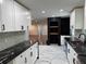 Bright kitchen featuring white cabinets, black countertops, and an open concept design with a black brick fireplace at 2899 Tejas Sw Trl, Atlanta, GA 30331