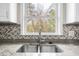 Close-up of a kitchen sink with granite countertops and a stylish herringbone backsplash at 2923 Hall Se Dr, Smyrna, GA 30082