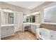 Bathroom with double sink vanity, soaking tub, tiled floor, and a window for natural light at 6445 Glen Oaks Ln, Sandy Springs, GA 30328