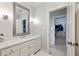 Bright bathroom featuring a large mirror, vanity with white countertops, and a view into the closet at 6955 Laurel Oak Dr, Suwanee, GA 30024