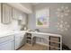 Neutral laundry room with patterned wallpaper, white cabinets, and a window with natural light at 6955 Laurel Oak Dr, Suwanee, GA 30024