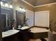 Bathroom featuring double vanity, soaking tub, and custom lighting at 3038 Mary Alice Trl, Loganville, GA 30052