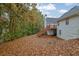 Spacious backyard featuring a wooden deck, lush greenery, and abundant autumn leaves at 777 Glen Valley Way, Dacula, GA 30019