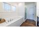 Bright bathroom featuring a subway tile tub surround, wood floors, glass shower door, and natural light at 902 E Ponce De Leon Ave, Decatur, GA 30030