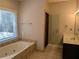 Bright bathroom with a soaking tub, walk-in shower, and a large window with blinds at 4401 Riverlake Way, Snellville, GA 30039