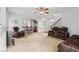 Large living room with a fireplace, tan walls, ceiling fan, and a view of the dining and kitchen areas at 4450 Sandalwood Way, Cumming, GA 30041