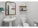 Well-appointed half-bathroom featuring a pedestal sink, toilet, and decorative shelves with stylish accents at 938 Blue Juniper Cir, Loganville, GA 30052