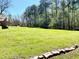 A wide shot of a yard, accented with a quaint stone path, bordering a lush, tree-filled landscape at 4267 Klondike Rd, Lithonia, GA 30038