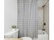 Tiled bathroom features a shower over tub with decorative patterned shower curtain and neutral walls at 2959 Rivergreen Se Ln, Atlanta, GA 30339
