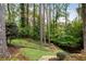 View of a lush backyard with a landscaped garden featuring mature trees, and stone steps at 5525 Whitner Dr, Sandy Springs, GA 30327