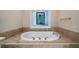 Beautiful soaking tub with tile surround and a decorative window at 5525 Whitner Dr, Sandy Springs, GA 30327