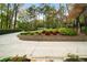 Curved concrete driveway with manicured landscaping, flower beds, and a retaining wall leading to the house at 5525 Whitner Dr, Sandy Springs, GA 30327