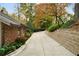 Long concrete driveway leading to a brick home surrounded by lush, colorful landscaping and a stone retaining wall at 5525 Whitner Dr, Sandy Springs, GA 30327