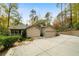 Beige house exterior with an attached garage, screened porch and a concrete driveway surrounded by lush trees at 5525 Whitner Dr, Sandy Springs, GA 30327
