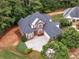 Aerial view of a brick two-story home with mature landscaping, a large driveway, and a two-car garage at 1258 Mcallistar Dr, Locust Grove, GA 30248