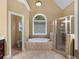 Bright bathroom featuring a soaking tub, tiled shower, and neutral color palette at 1258 Mcallistar Dr, Locust Grove, GA 30248