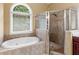 Bathroom showcasing a soaking tub, tiled shower, and a window providing natural light at 1258 Mcallistar Dr, Locust Grove, GA 30248