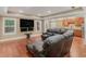 Living room with a sectional leather couch facing two windows and a large screen television at 1258 Mcallistar Dr, Locust Grove, GA 30248