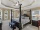 Luxurious main bedroom with a four-poster bed, tray ceilings, and large windows providing natural light at 1258 Mcallistar Dr, Locust Grove, GA 30248