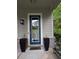 Stylish front door with glass panel, flanked by tall planters, offering a warm entrance to the home at 3157 Oakdale Rd, Hapeville, GA 30354