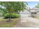 View of the two-car garage with a concrete driveway and mature trees at 3157 Oakdale Rd, Hapeville, GA 30354