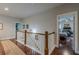 Upstairs hallway with wood floors and white railings overlooking a bedroom with a ceiling fan at 3157 Oakdale Rd, Hapeville, GA 30354