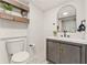 Modern bathroom with sleek gray vanity, marble floors, arched mirror, and stylish wooden shelving at 2111 Drew Valley Ne Rd, Brookhaven, GA 30319