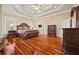 A luxurious main bedroom with a tray ceiling, dark wood furniture, and gleaming hardwood floors at 3591 Lochwolde Ln, Snellville, GA 30039