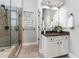 Main bathroom vanity featuring marble countertop, framed mirror, white cabinets, and a tiled glass shower at 1845 Habersham Trce, Cumming, GA 30041