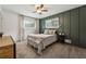 Cozy bedroom featuring a decorative green accent wall, plush carpeting, and natural light from two windows at 4072 Whispering Forest Ct, Lilburn, GA 30047