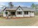 Rear exterior of a cozy cottage-style home with a covered porch, chimney, and well-maintained lawn in a serene setting at 5975 P W A Dr, Cumming, GA 30041