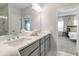 Bright bathroom featuring a double sink vanity with gray cabinets, a large mirror, white marble and glass shower at 6785 Pippin Walk, Alpharetta, GA 30005