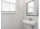 Clean, well lit bathroom with a pedestal sink, a large mirror, and a window for natural light at 6785 Pippin Walk, Alpharetta, GA 30005